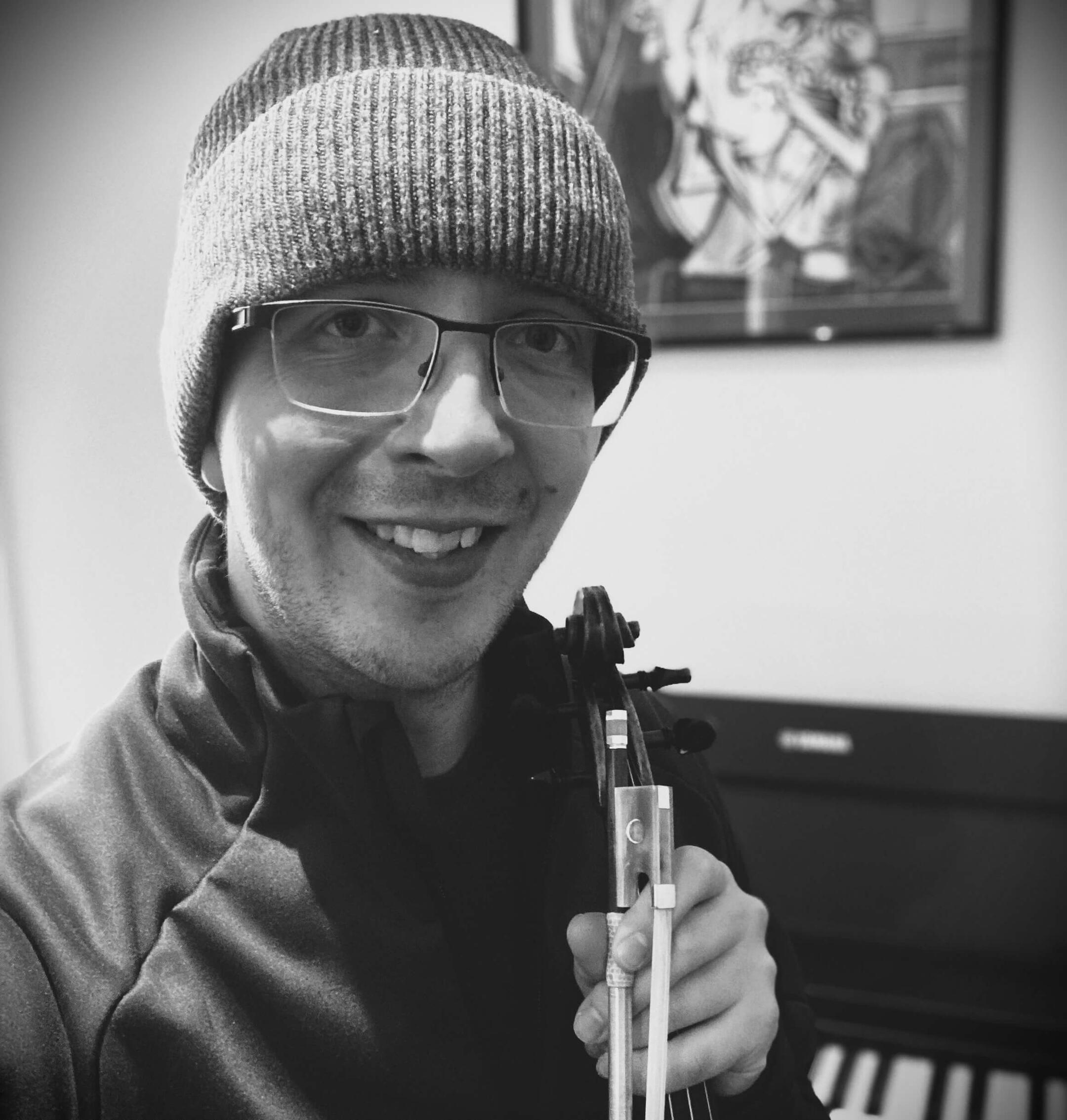 Henry Bentley Professional music teacher posing with violin and piano for teaching and performance.